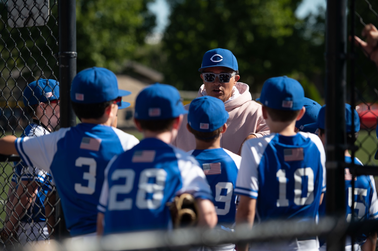 Brooklyn Cadets 12U baseball players huddled around Coach Jose Franco in royal-blue uniforms before a game — photo by Matthew Bencivenga